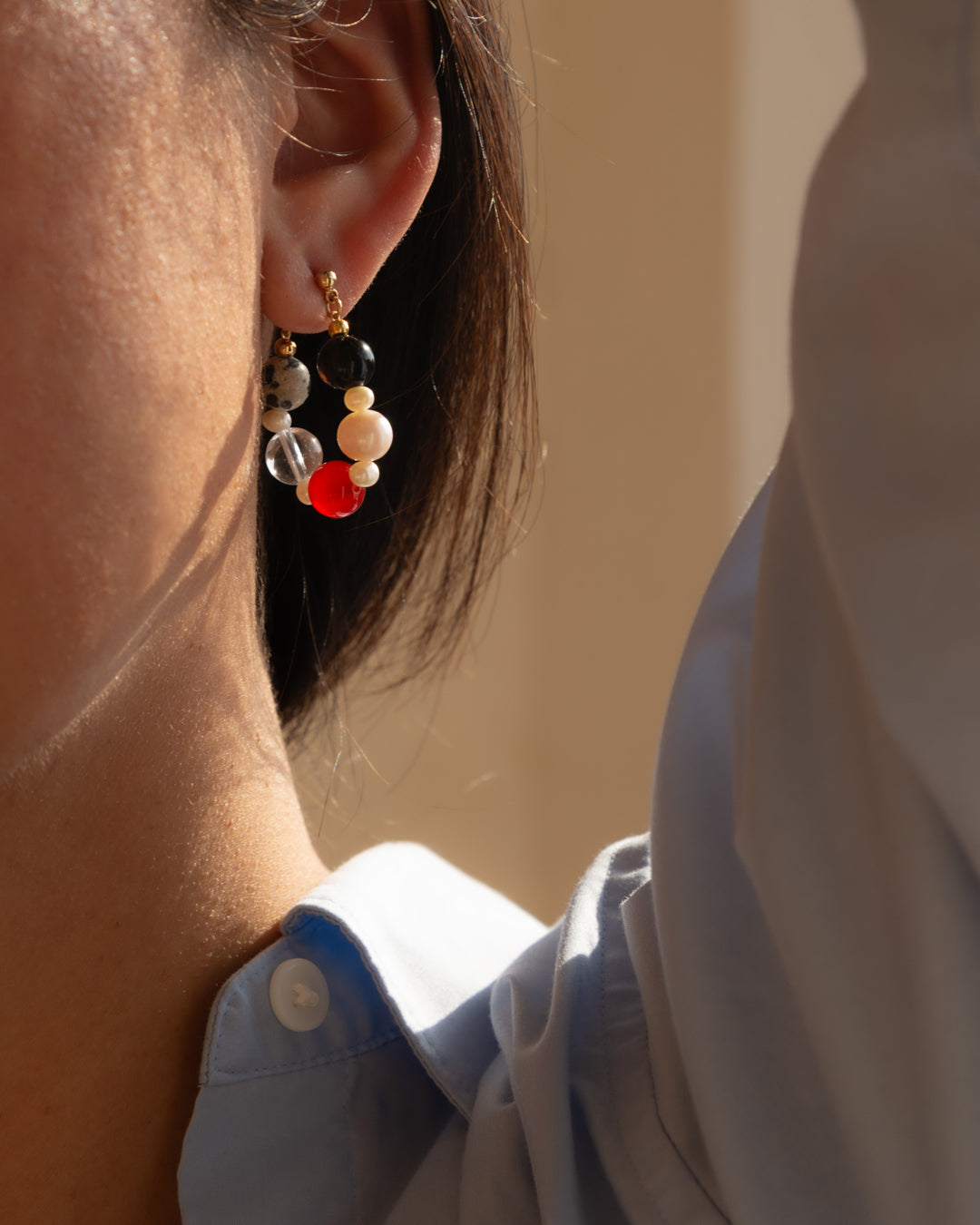 Boba earrings, a colorful combination of onyx, red agate, freshwater pearl, clear quartz and Dalmatian jasper, adorning a person with confident and no-nonsense outfit.