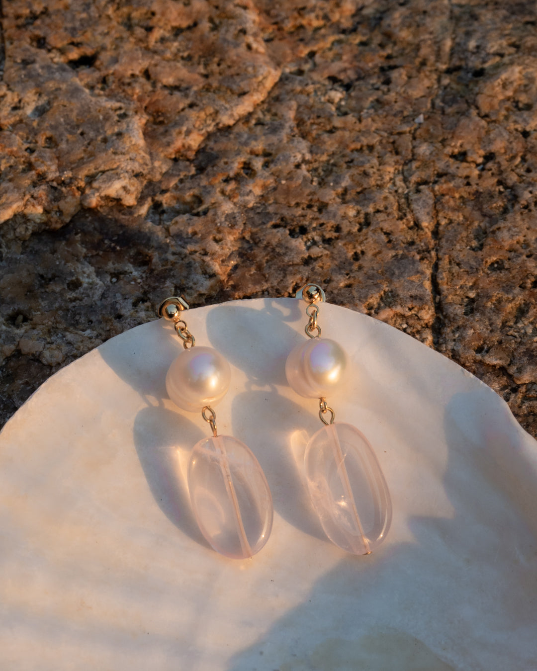 Sparkling Earrings: Pink Quartz and Freshwater Pearl earrings on a mother of pearl's shell, capturing light and elegance.