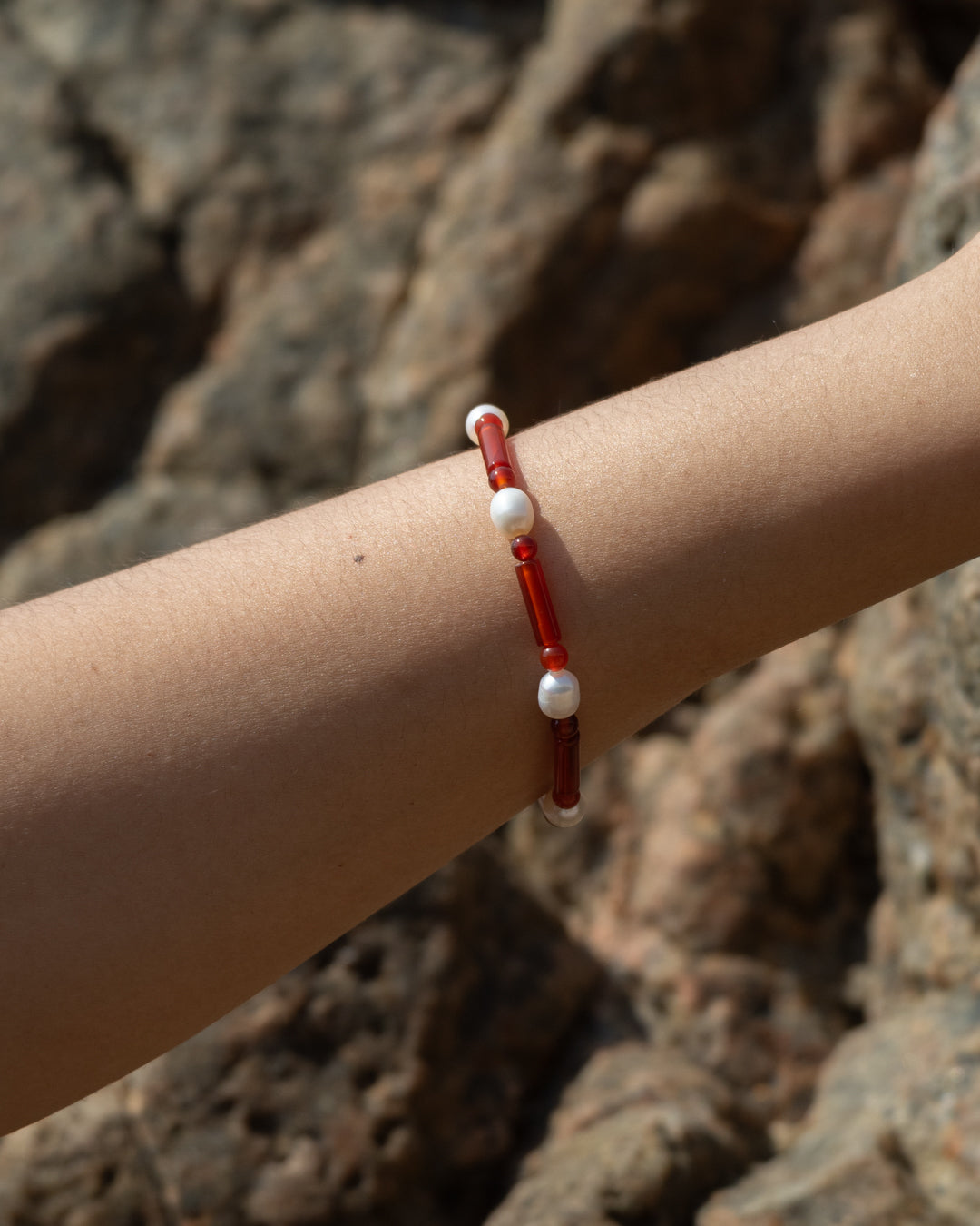 Stylish red agate bracelet featuring a freshwater pearl, showcasing Starry Bracelet Red Agate's vibrant color and elegant design against a natural backdrop.