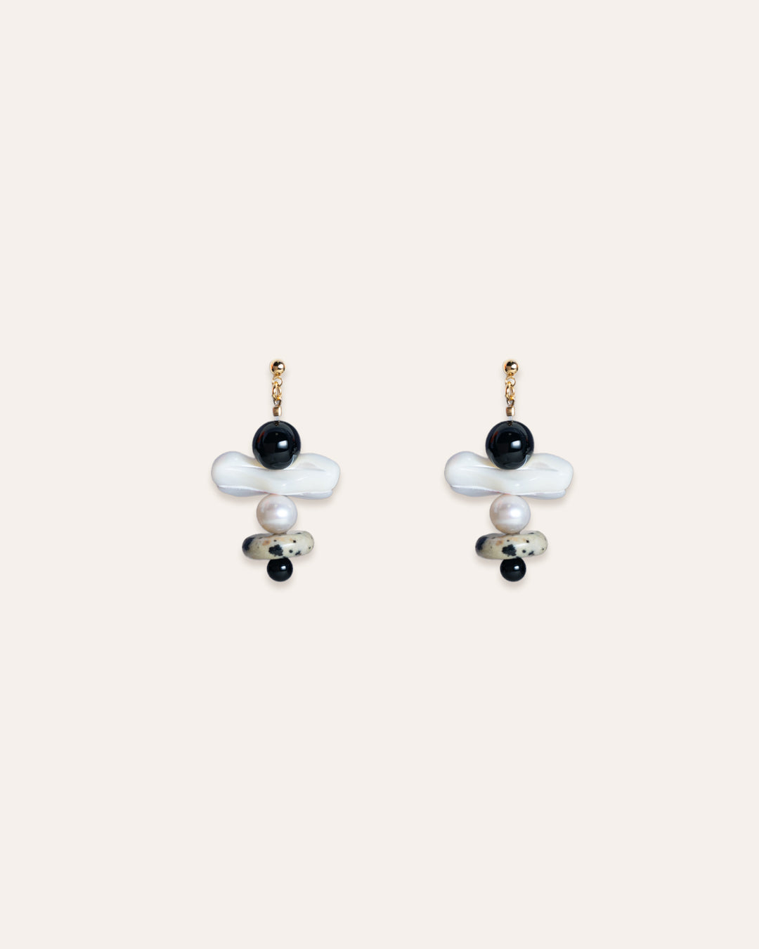 A pair of Tulip Earrings, crafted from exquisite materials-mother of pearl, freshwater pearl, onyx, and dalmatian jasper. These earrings exhibit a harmonious blend of textures and colors, with the pearls providing a lustrous sheen and the black stones adding an elegant contrast. The design includes delicate details that enhance the overall appeal of the earrings. These pieces of jewelry are perfect for enhancing one's style and can be worn on various occasions.