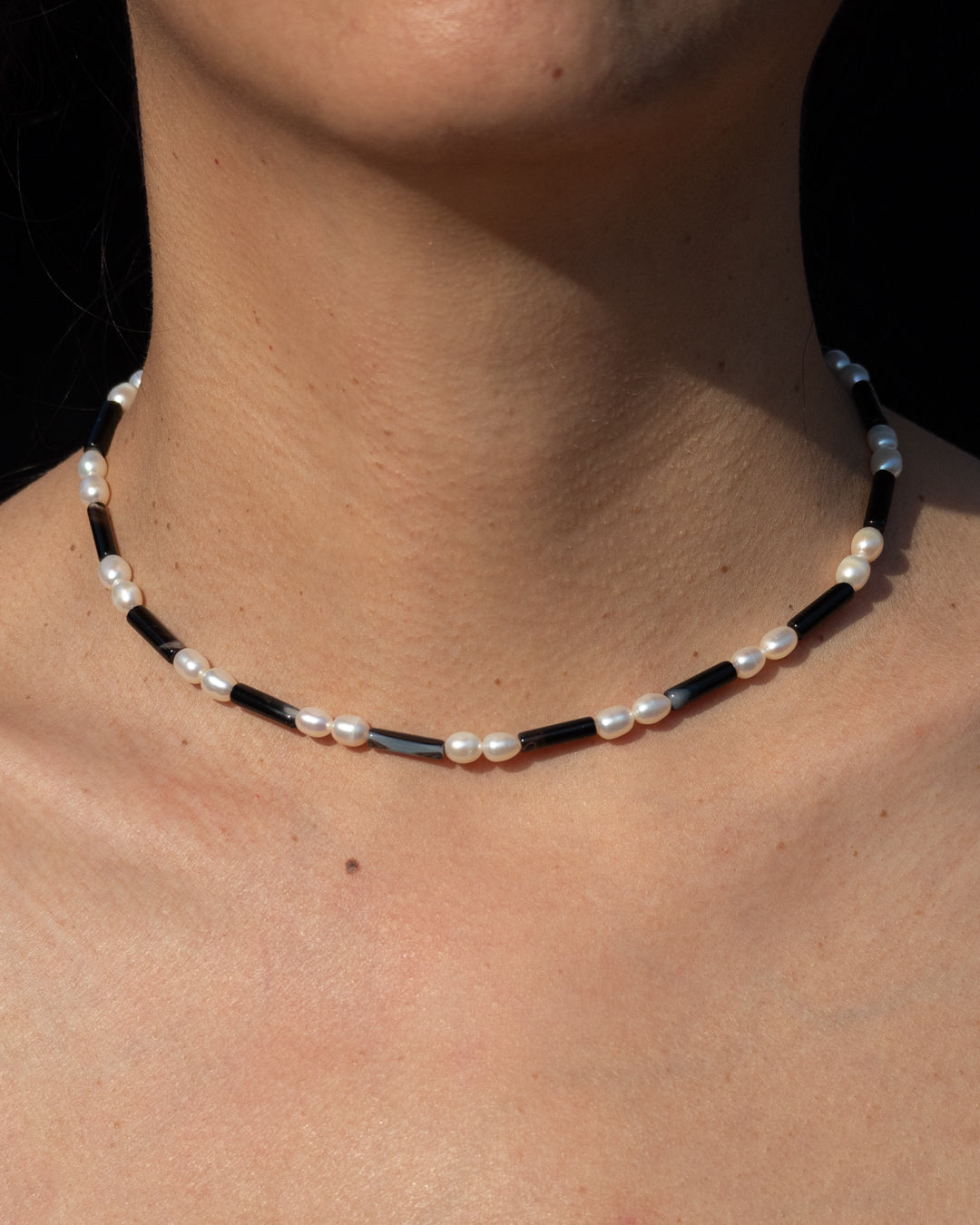 Rhythm Necklace in Onyx featuring freshwater pearls. Designed to accentuate style and fashion. This statement piece adds a touch of elegance to any outfit. Made with high-quality materials, the necklace is perfect for everyday wear or special occasions. The black onyx complements the natural sheen of the pearls, creating a striking contrast. Purchase now to elevate your look! 